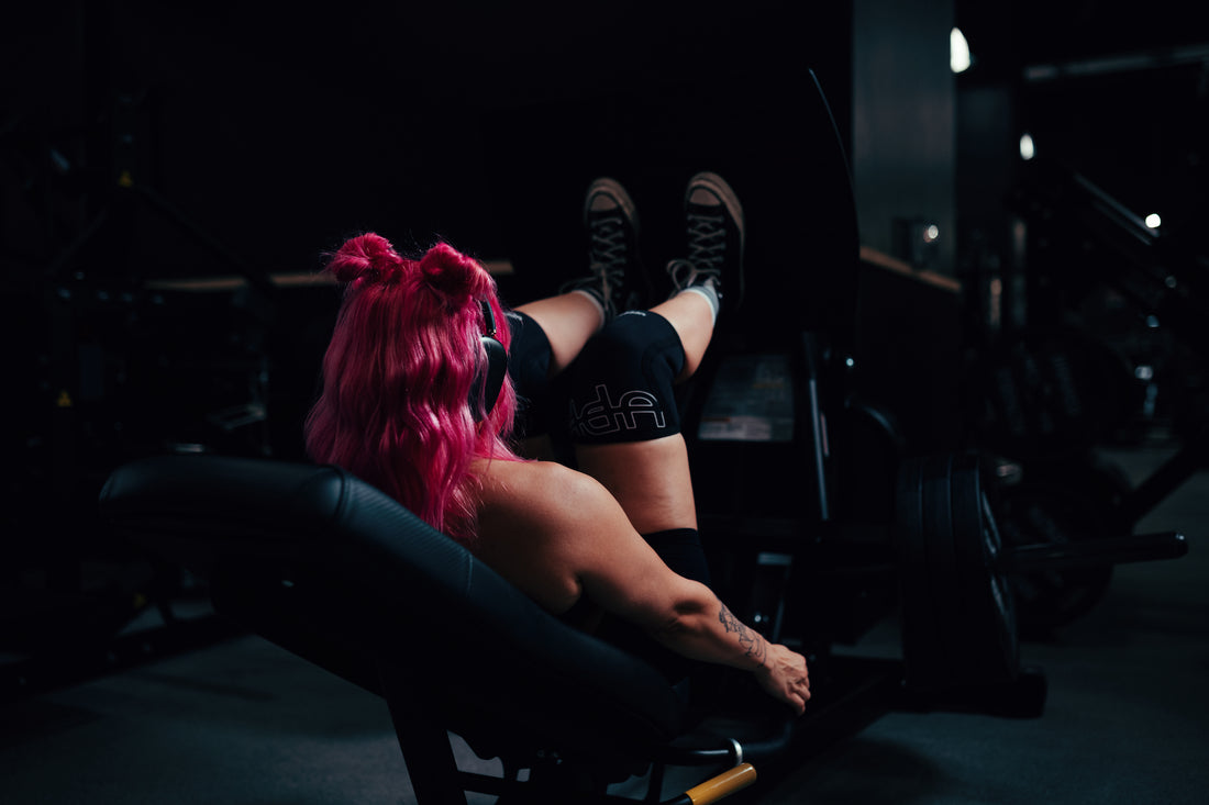 woman doing the leg press machine with uppper knee sleeves