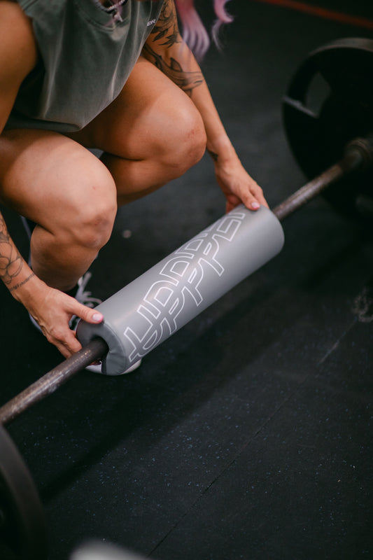 woman wrapping uppper barbell pad on barbell